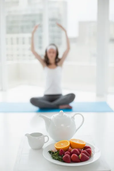 Mujer borrosa en postura de meditación con comida saludable en primer plano — Foto de Stock