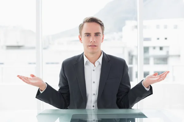 Displeased businessman with hand gesture at office desk — Stock Photo, Image