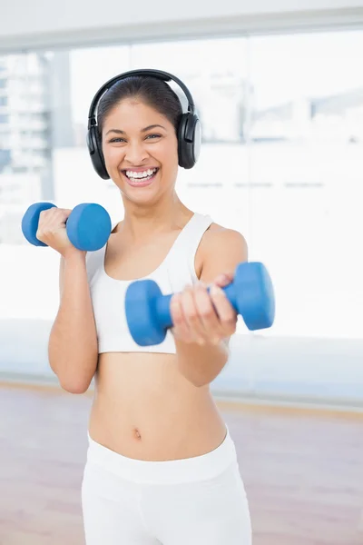 Mulher alegre exercitando com halteres no estúdio de fitness — Fotografia de Stock