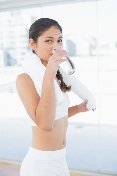 Mulher com toalha em torno do pescoço água potável no estúdio de fitness — Fotografia de Stock