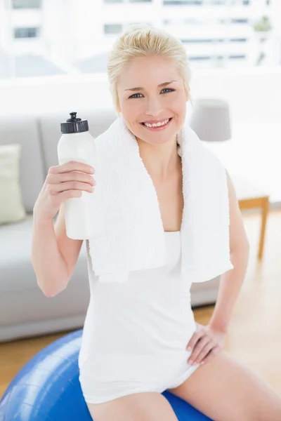 Fit mujer beber agua mientras está sentado en la pelota de ejercicio —  Fotos de Stock