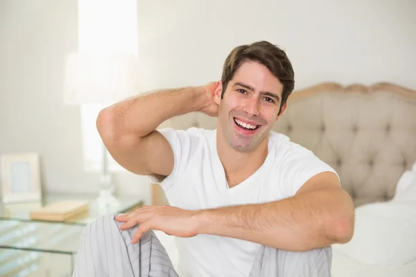 Retrato de um homem sorridente sentado na cama — Fotografia de Stock