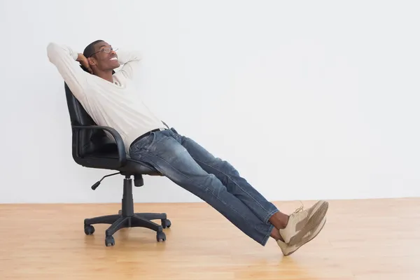Nachdenklicher, lässiger Afro-Mann sitzt auf Bürostuhl im leeren Raum — Stockfoto