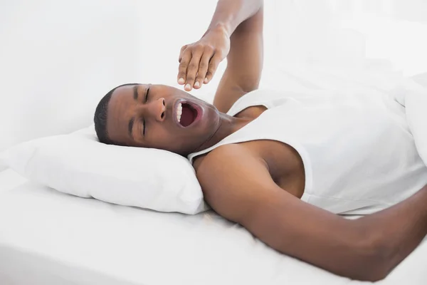 Schläfriger Afro-Mann gähnt im Bett — Stockfoto