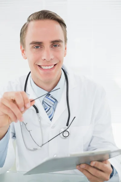 Médico masculino sonriente mirando la tableta digital —  Fotos de Stock