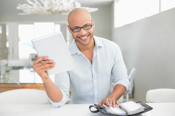 Příležitostné usmívající se muž s digitálním tabletu a deník doma — ストック写真
