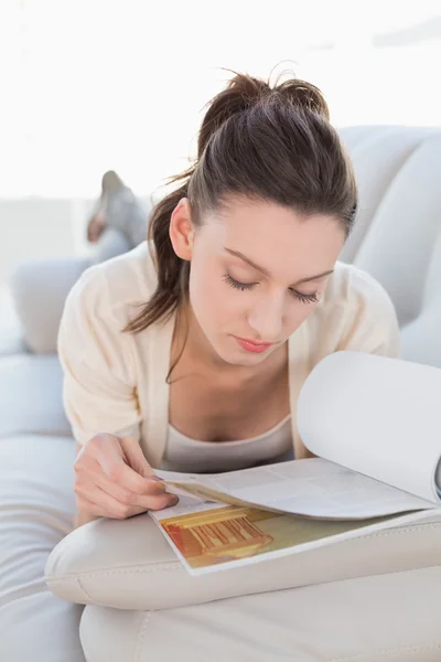 Rilassato donna casual leggere un libro sul divano — Foto Stock