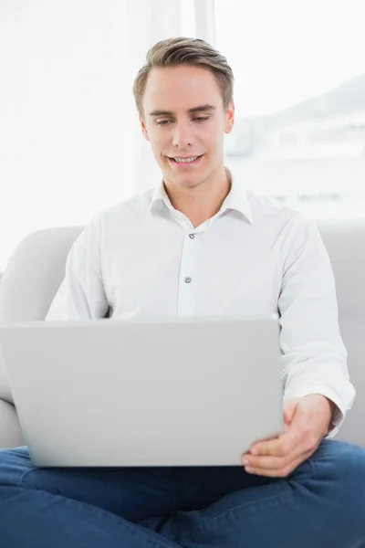 Retrato de um jovem casual usando laptop no sofá — Fotografia de Stock