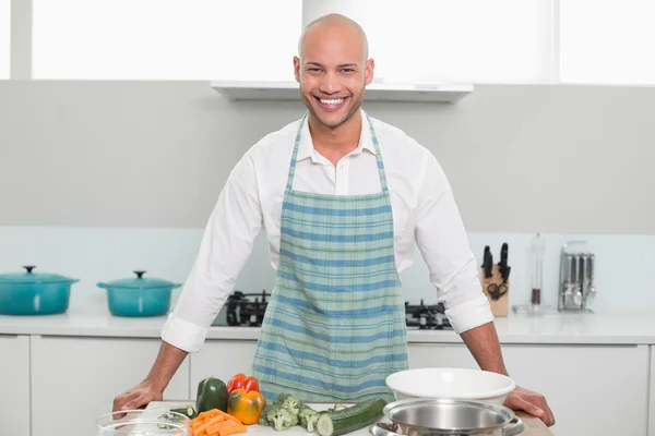 Jovem sorridente com legumes na cozinha — Fotografia de Stock