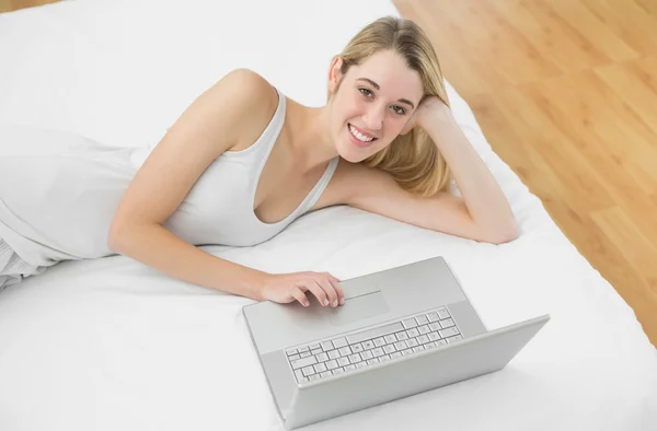 Cheerful blonde woman using her notebook smiling at camera — Stock Photo, Image