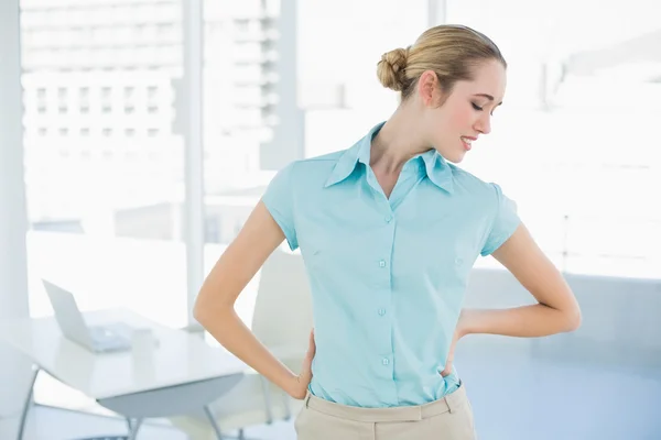 Gorgeous suffering businesswoman holding her injured back — Stock Photo, Image