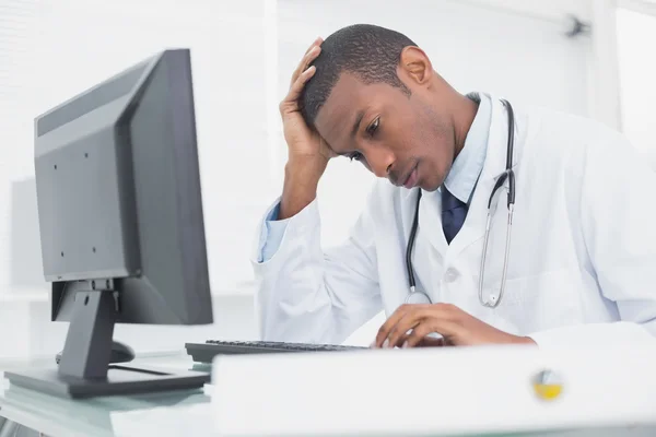 Besorgter männlicher Arzt nutzt Computer — Stockfoto