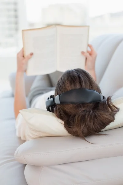 Mujer de cabello castaño disfrutando de la música mientras lee libro —  Fotos de Stock