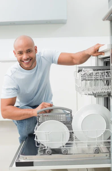 Портрет улыбающегося мужчины с посудомоечной машиной на кухне — стоковое фото