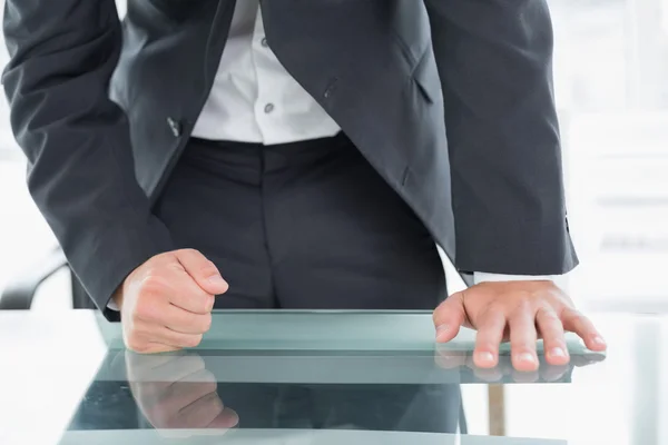 Mid section of businessman with clenched fist on office desk — Stock Photo, Image