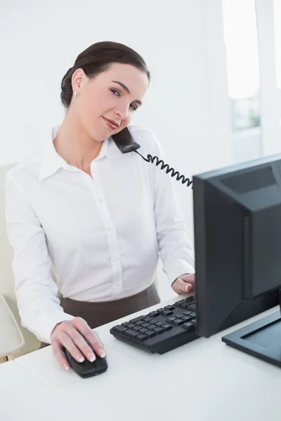 Empresária concentrada que utiliza computador e telefone — Fotografia de Stock