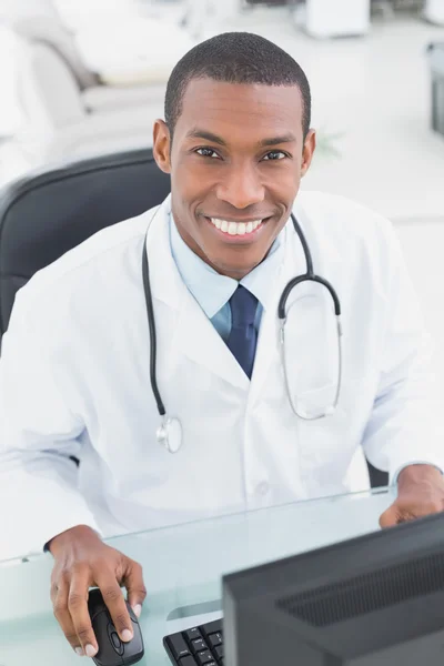 Médico sorrindo usando o computador no consultório médico — Fotografia de Stock