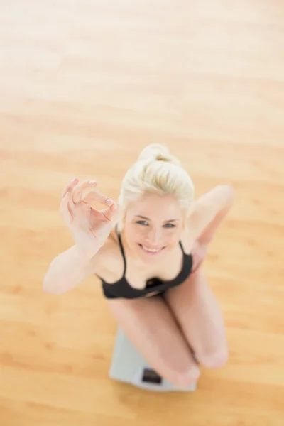 Mujer alegre gesto ok signo a escala en el gimnasio — Foto de Stock