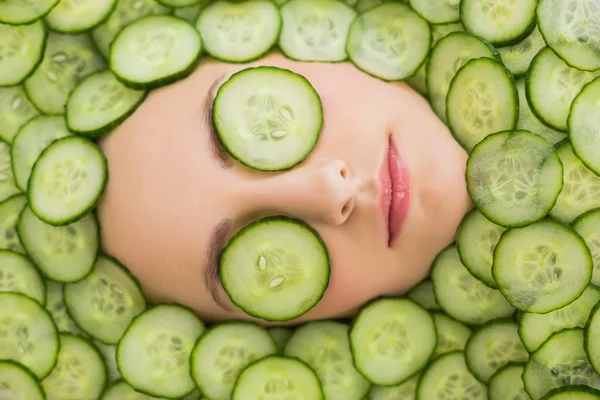 Beautiful woman with facial mask of cucumber slices on face — Stock Photo, Image