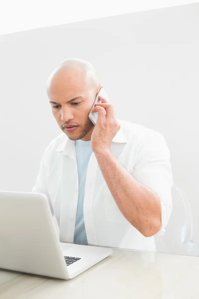 Casual serious man using cellphone and laptop at desk — Stock Photo, Image