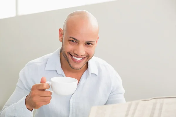 Homme souriant prenant un café tout en lisant le journal — Photo