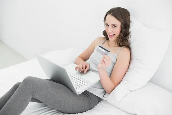 Casual ung kvinna gör online shopping i sängen — Stockfoto