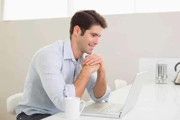 Casual leende man använder laptop hemma — Stockfoto