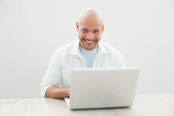 休闲的男人微笑着在桌子上使用笔记本电脑的肖像 — 图库照片