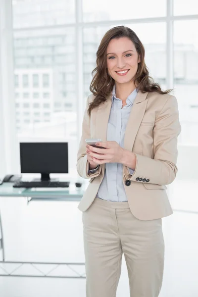 Sonriente elegante mujer de negocios de mensajes de texto en la oficina — Foto de Stock