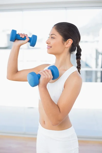 Woman exercising with dumbbells in fitness studio — Stock Photo, Image