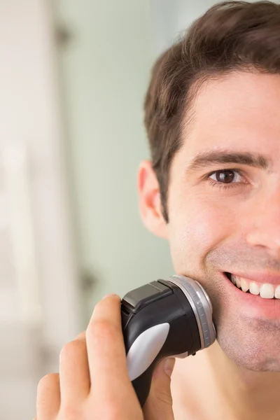 Close up of smiling man shaving with electric razor — Stock Photo, Image