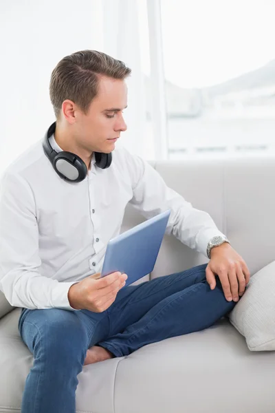 Casual serious young man using digital tablet on sofa — Stock Photo, Image