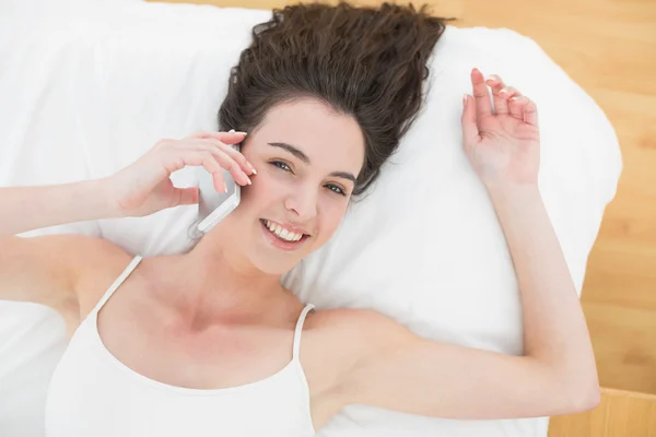 Retrato de mulher relaxada usando telefone celular na cama — Fotografia de Stock