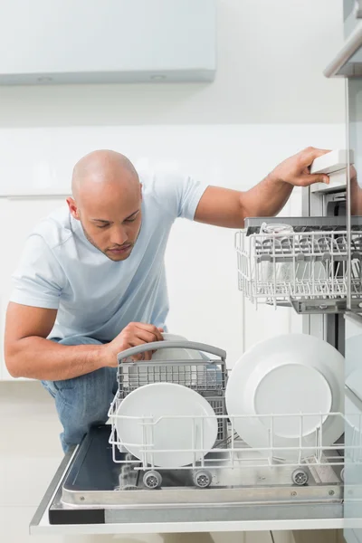 Hombre serio usando lavavajillas en la cocina —  Fotos de Stock