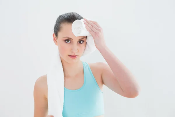 Woman wiping sweat with towel against wall — Stock Photo, Image