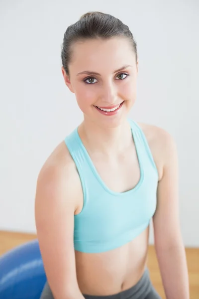 Mujer en forma sentada en la pelota de ejercicio en el estudio de fitness —  Fotos de Stock