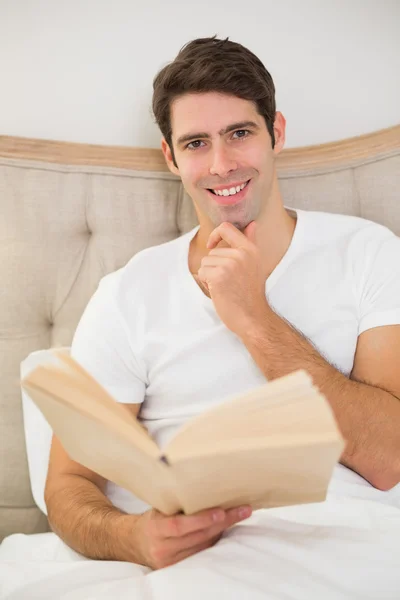 Portrét uvolněné mladého muže, čtení knihy v posteli — Stock fotografie
