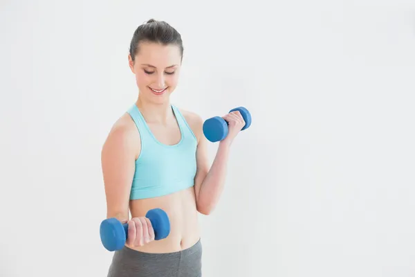 Mujer sonriente con mancuernas en el gimnasio — Foto de Stock