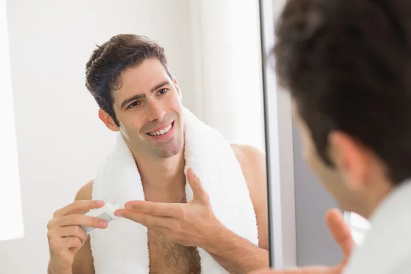 Man with reflection putting moisturizer on his face — Stock Photo, Image