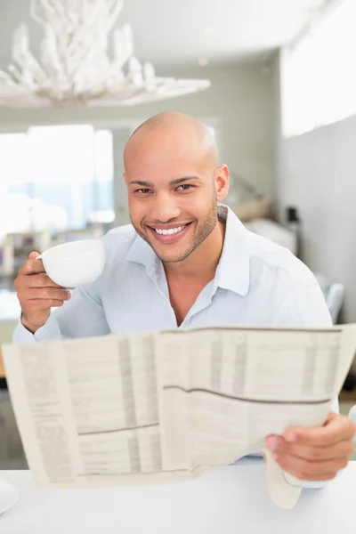 新聞を読みながらコーヒーを飲んで笑みを浮かべて男 — Stock fotografie