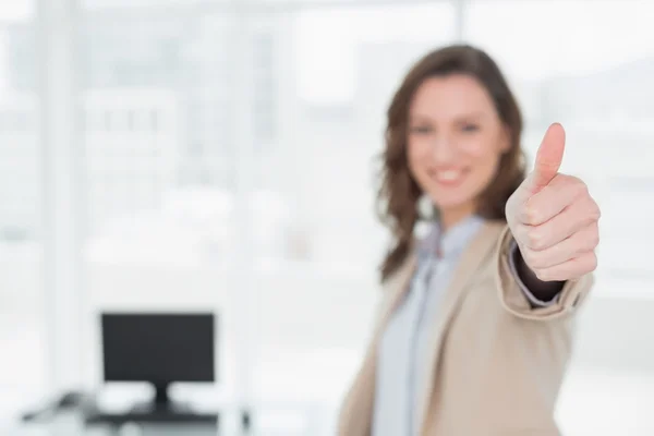 Элегантная улыбающаяся деловая женщина, показывающая пальцами вверх в офисе — стоковое фото