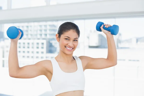 Fit woman exercising with dumbbells in fitness studio — Stock Photo, Image