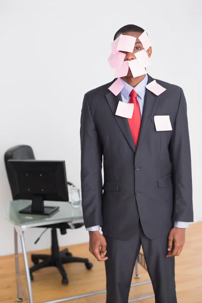 Businessman covered in blank notes at office — Stock Photo, Image