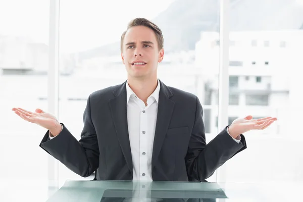 Displeased businessman with hand gesture at office desk — Stock Photo, Image