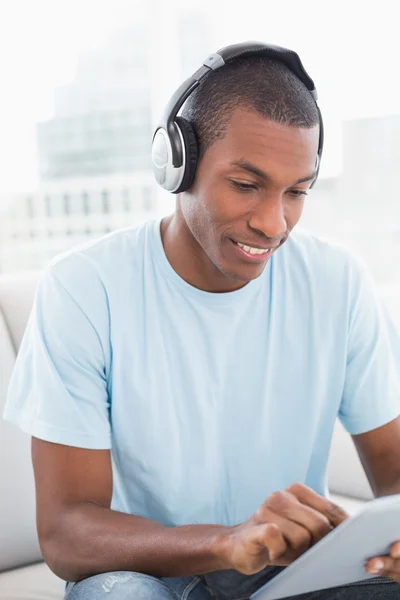 Afro man wearing headphones while using digital tablet on sofa — Stock Photo, Image