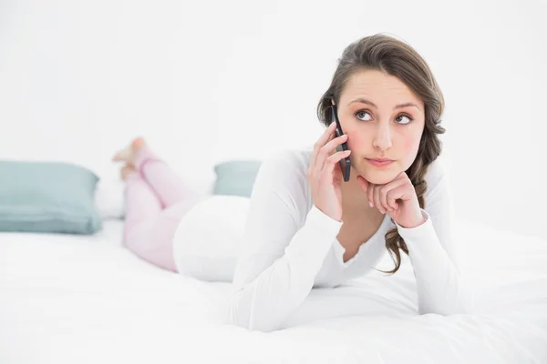 Mujer reflexiva usando el teléfono móvil en la cama — Foto de Stock