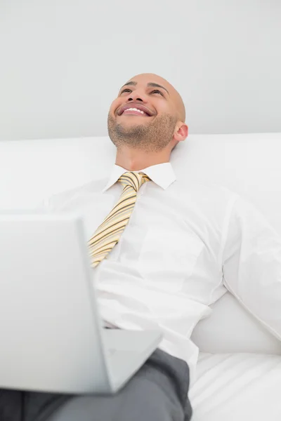 Businessman looking up while using laptop — Stock Photo, Image
