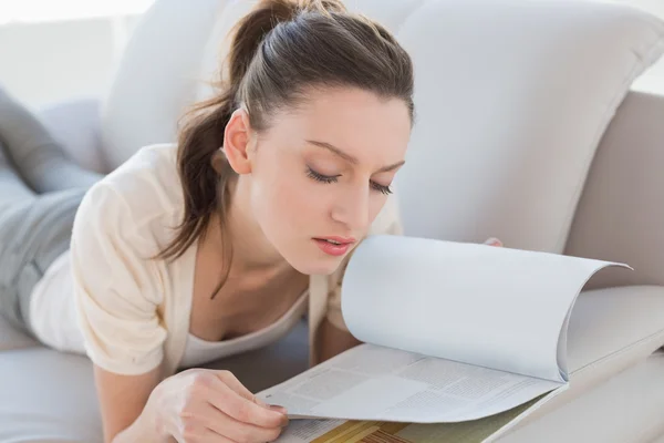 Relajada mujer casual leyendo un libro en el sofá — Foto de Stock