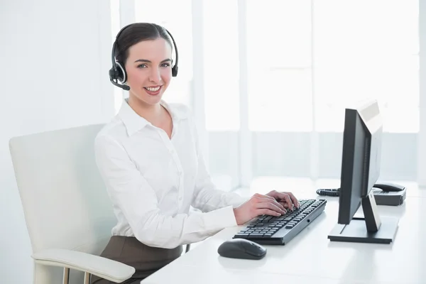 Donna d'affari che indossa auricolari durante l'utilizzo del computer — Foto Stock