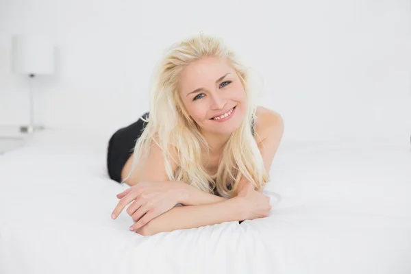 Portret van een glimlachende blond liggend in bed — Stockfoto